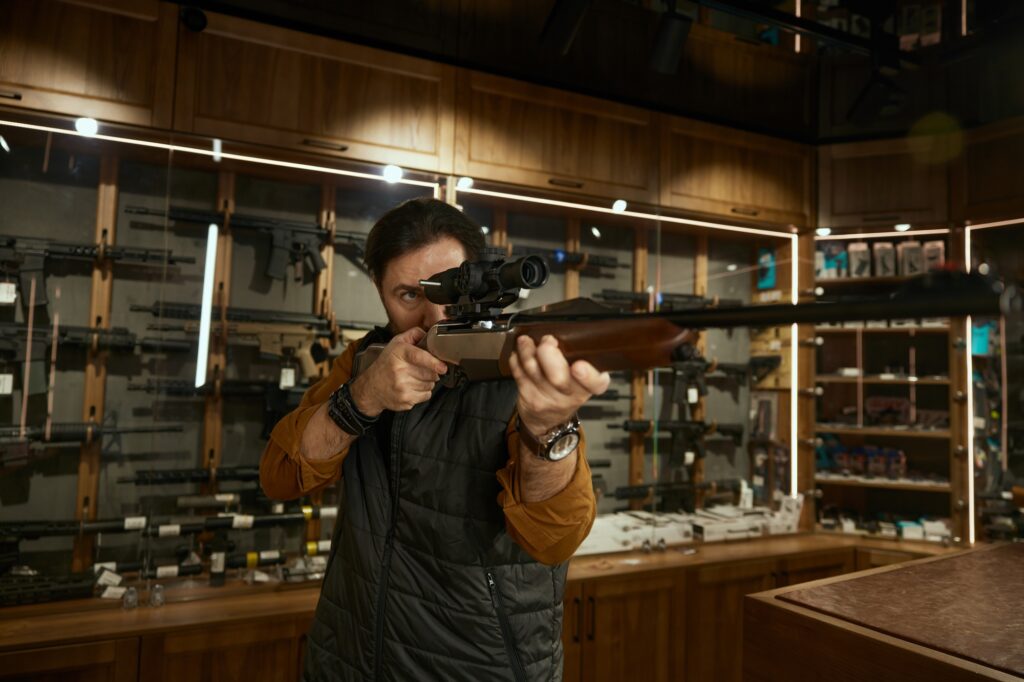 Man entrepreneur checking gun aiming telescopic sight at weapon store